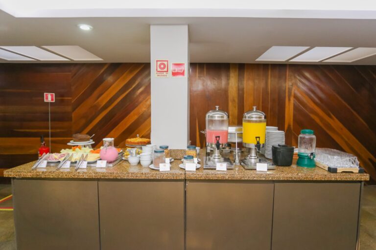 Bancada do café da manhã com frios, sucos, bolos e as estações de bebidas