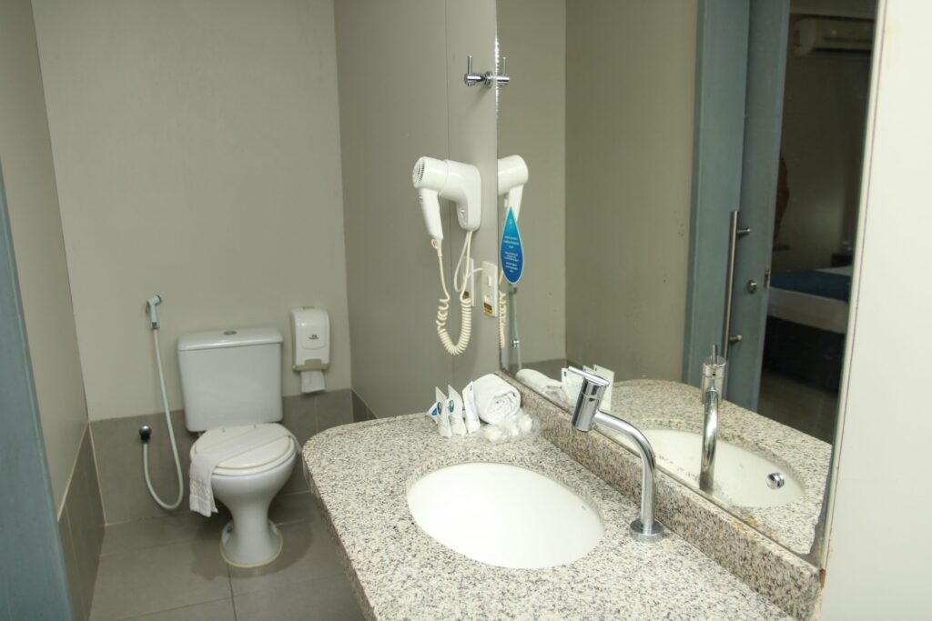 Banheiro do apartamento Luxo com pia, espelho e secador de cabelo