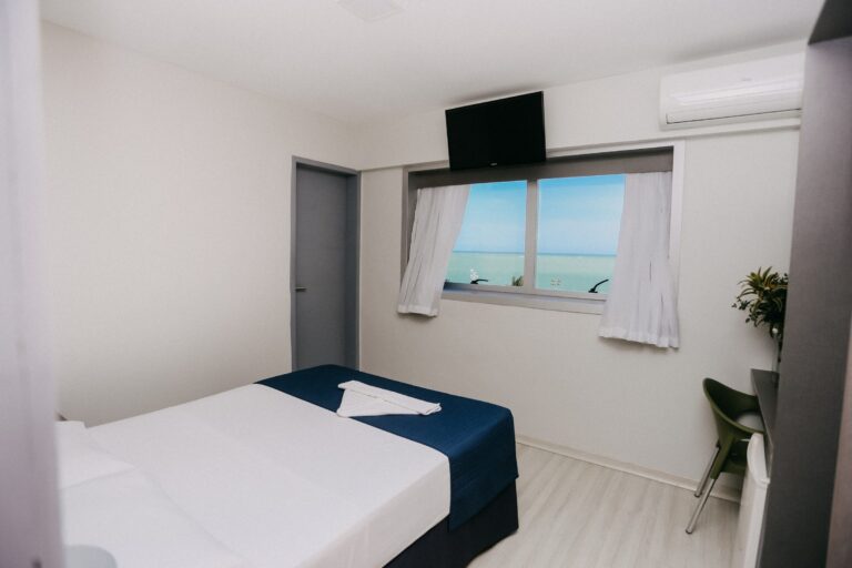 Apartamento Luxo com cama de casal, TV e janela com vista para o mar