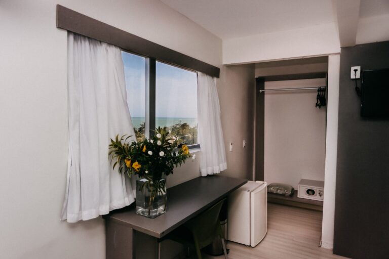 Escrivaninha com flores, frigobar e janela com vista para o mar no apartamento Luxo