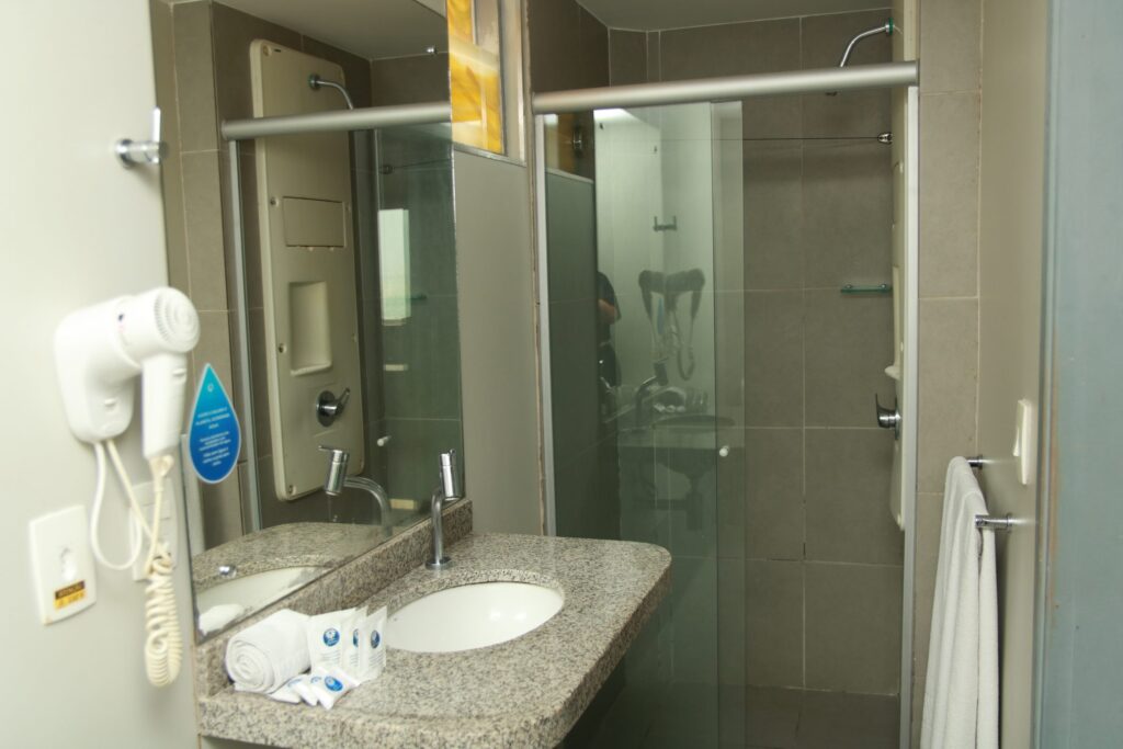 Banheiro do apartamento Standard com box de vidro, bancada e secador de cabelo