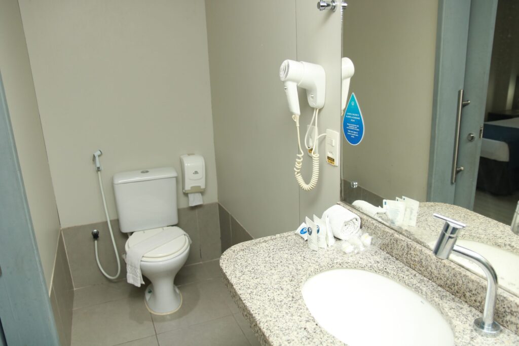 Banheiro do apartamento Standard com pia, espelho e secador de cabelo